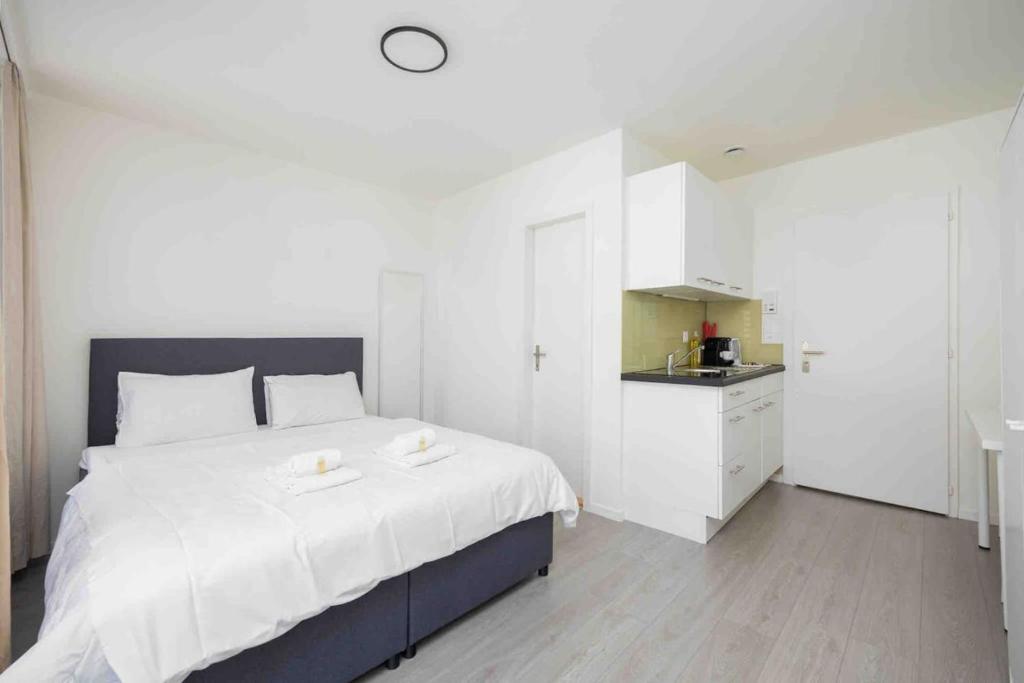 a white bedroom with a large bed and a kitchen at Downtown Deluxe Studio with Queen Bed BE-35 in Zurich