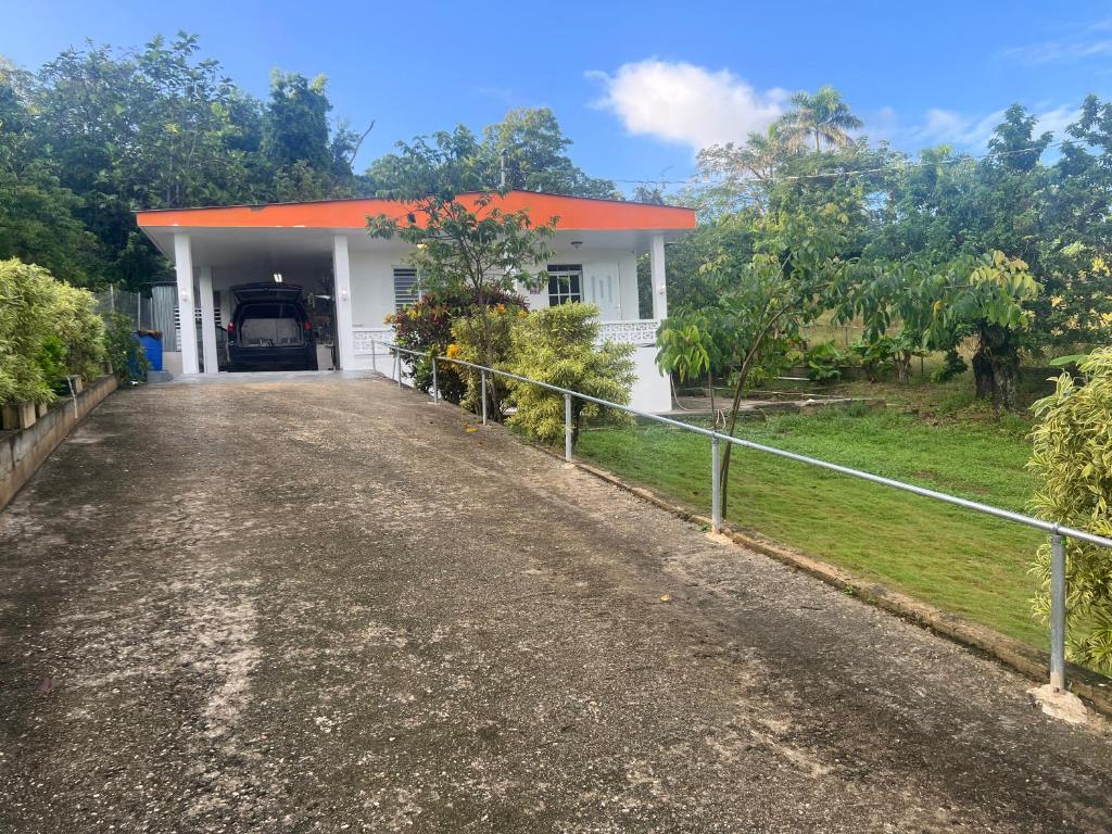 a white house with an orange roof and a driveway at Coqui del corazón Guest House in Hatillo