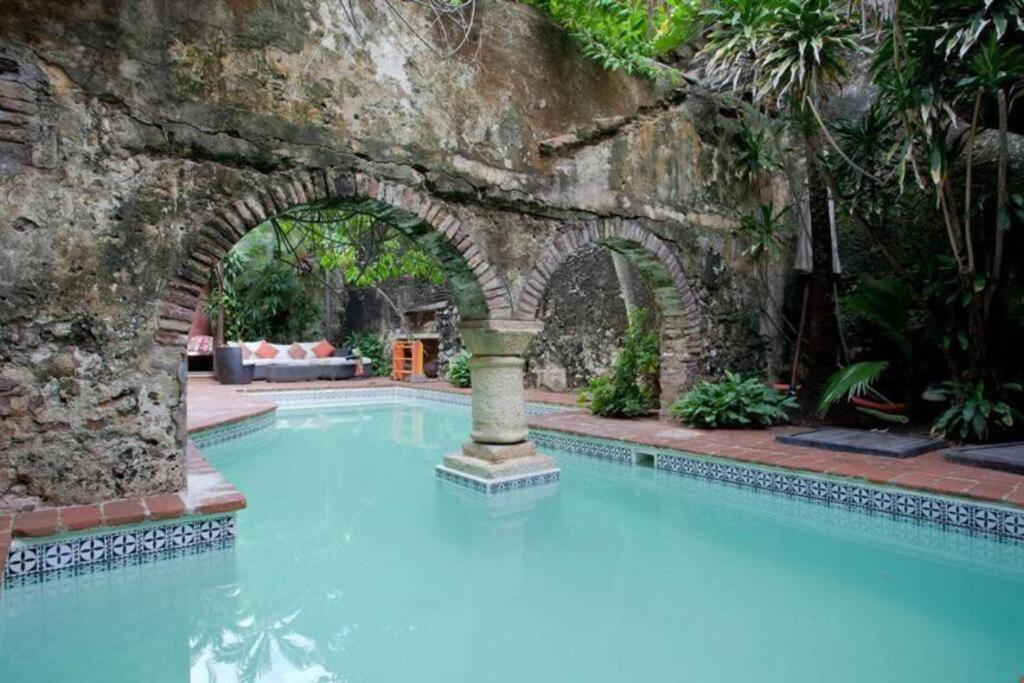 una piscina con una pared de piedra y un arco en Magnificent Colonial Mansion en Cartagena de Indias
