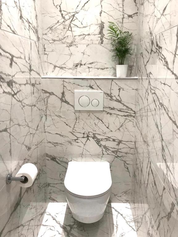 a bathroom with a white toilet and a marble wall at Antares Luxury Rooms 2 in Split