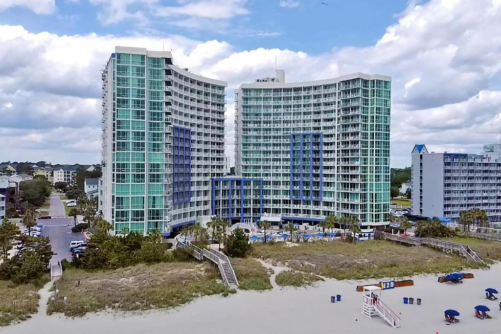 two tall buildings in front of a beach with buildings at Avista Resort in Myrtle Beach