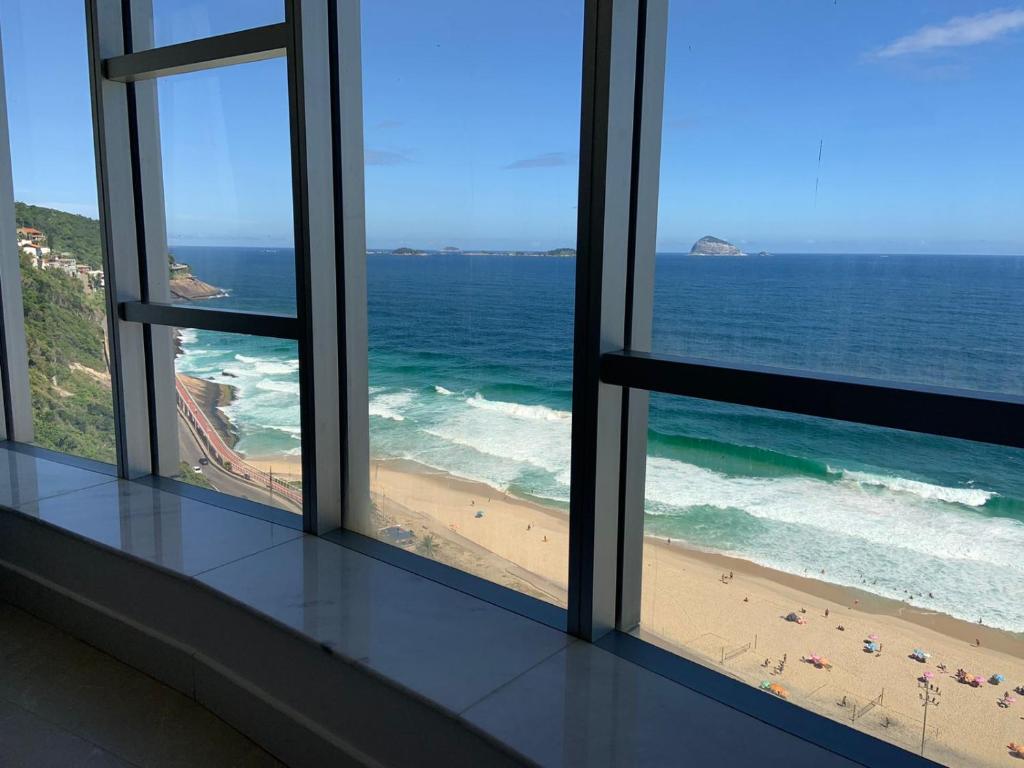 uma vista para a praia a partir de um quarto com janelas em Hotel Nacional RJ - Vista Mar no Rio de Janeiro
