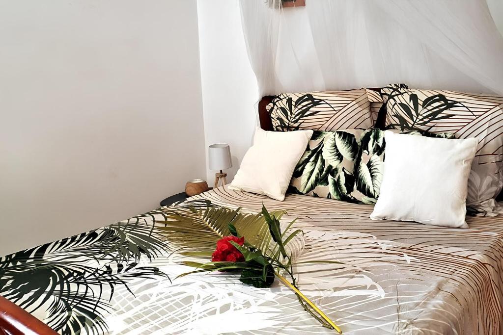 Un dormitorio con una cama con un arreglo floral. en Couleurs caraïbes - Plage et Tranquillité en Sainte-Anne