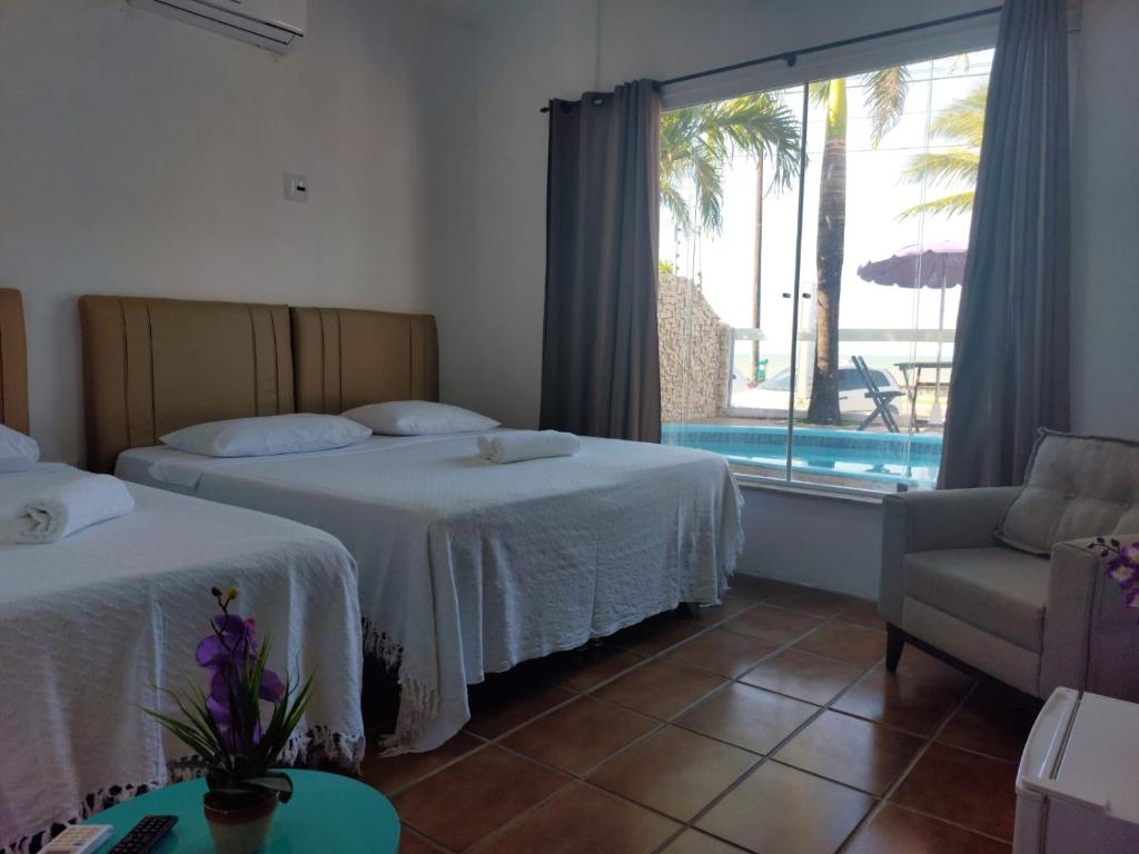 a bedroom with two beds and a chair and a window at POUSADA STYLLUS in João Pessoa