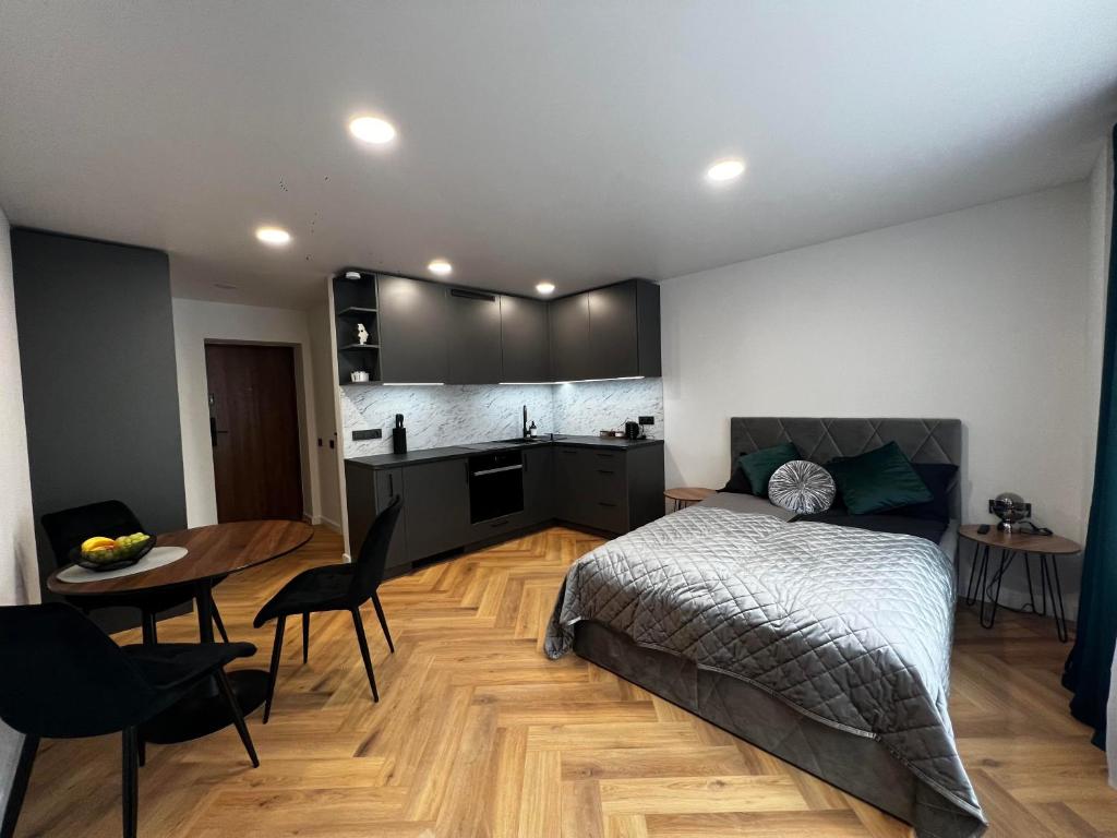 Un dormitorio con una cama y una mesa y una cocina. en Hygge Apartments, en Druskininkai