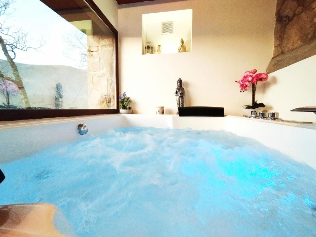 y baño con bañera grande llena de agua azul. en Apartamentos La Rosa y El Pastor, en Guijo de Santa Bárbara
