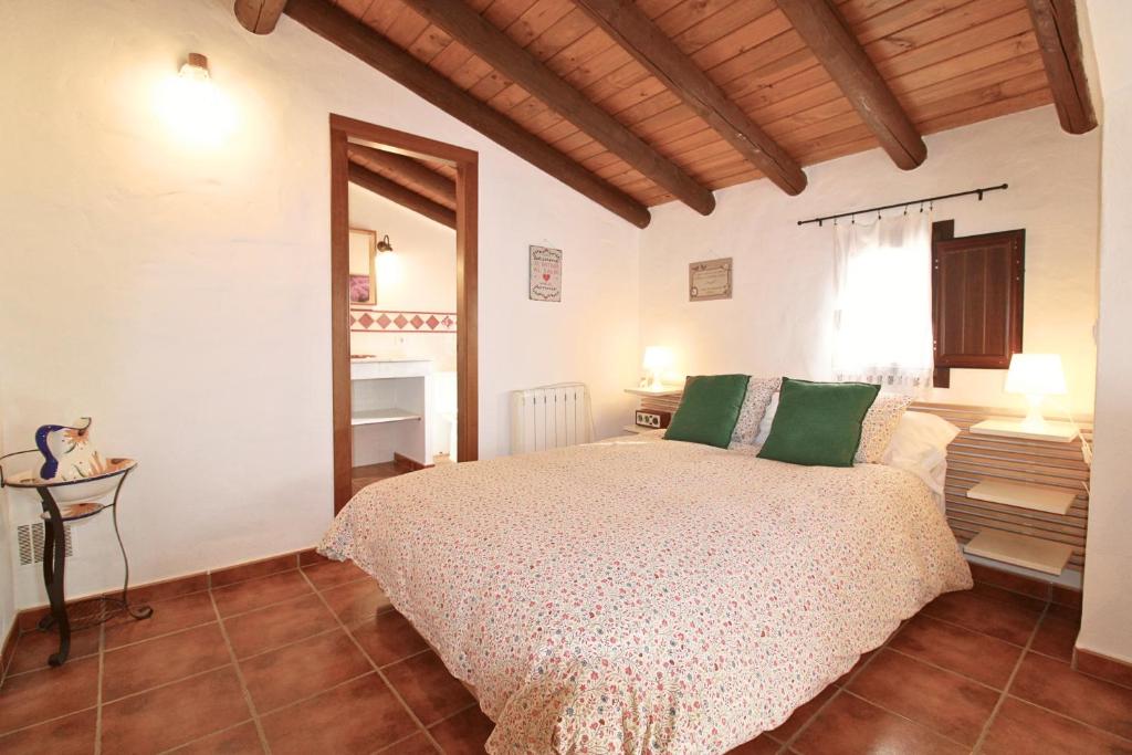 Un dormitorio con una cama con almohadas verdes. en La Solana by SIERRA VIVA, en Cortelazor