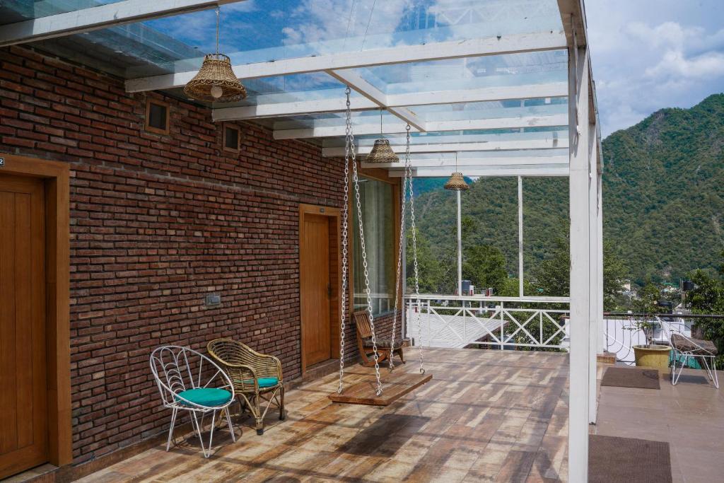 a patio with chairs and a glassconservatory with mountains at Swiss Cottage and Spa by Salvus in Rishīkesh