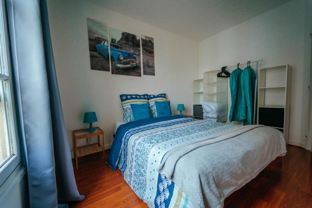 una camera con letto e lenzuola bianche e blu di Appartement 1 chambre Les Lumières avec parking sous-sol a Chartres