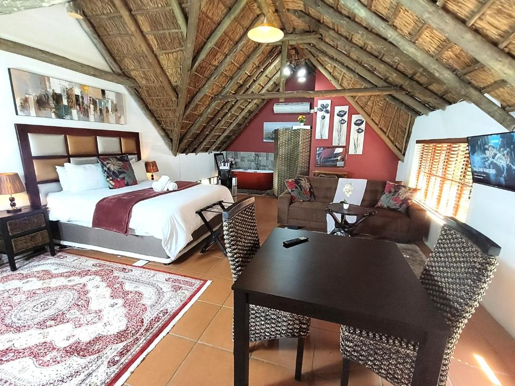 1 dormitorio con 1 cama, mesa y sillas en Lipizzaner Lodge en Kyalami