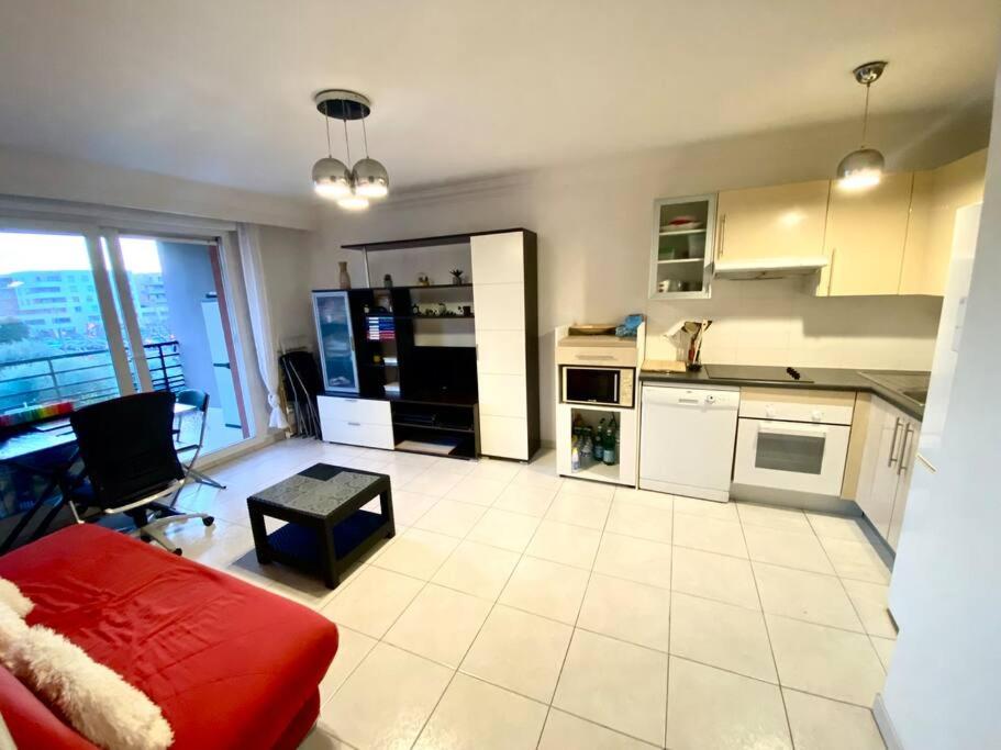 a kitchen with white appliances and a red couch at Nice Ouest St Isidore- 2P au calme in Nice