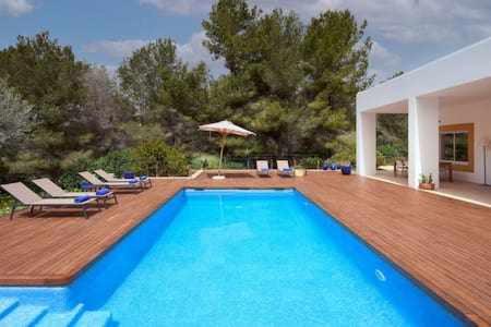 une grande piscine bleue sur une terrasse en bois dans l'établissement Can coll des cocons barefoot house 5min from pacha, à Ibiza