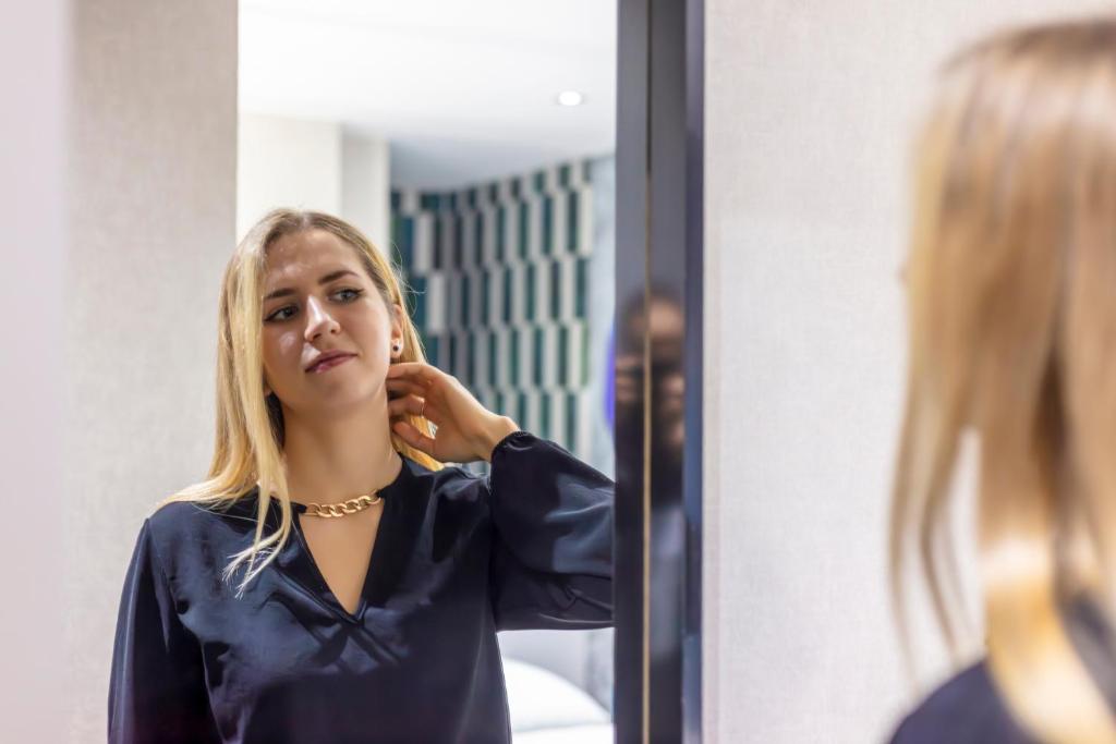 a woman brushing her hair in front of a mirror at Dem Premium Hotel - Round Trip Airport Service - Istanbul International Airport in Arnavutköy