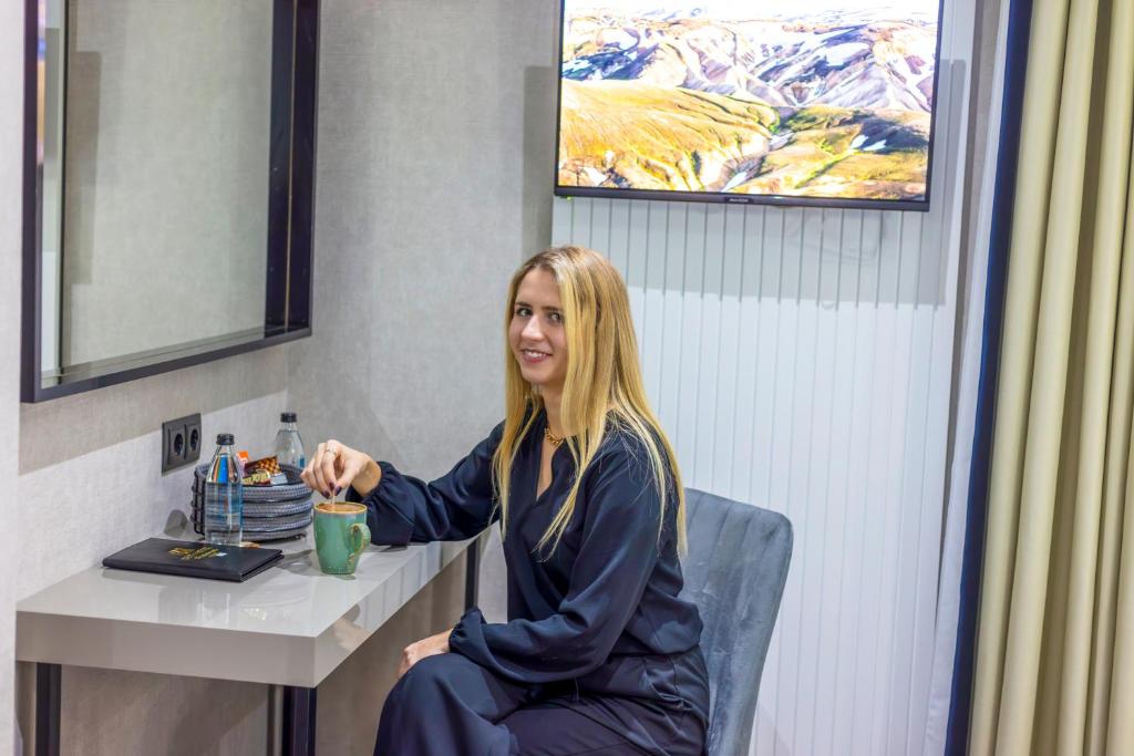 a woman sitting at a table in a room at Dem Premium Hotel - Round Trip Airport Service - Istanbul International Airport in Arnavutköy