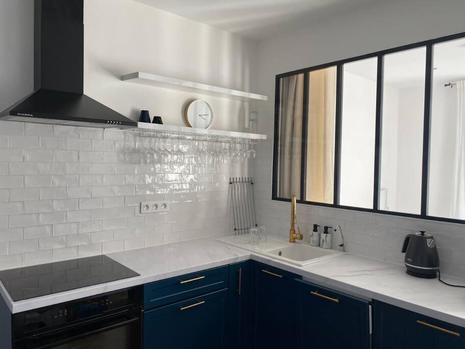 eine Küche mit blauen Schränken, einem Waschbecken und einem Fenster in der Unterkunft Beau 2 pièces - Mairie de Clichy in Clichy