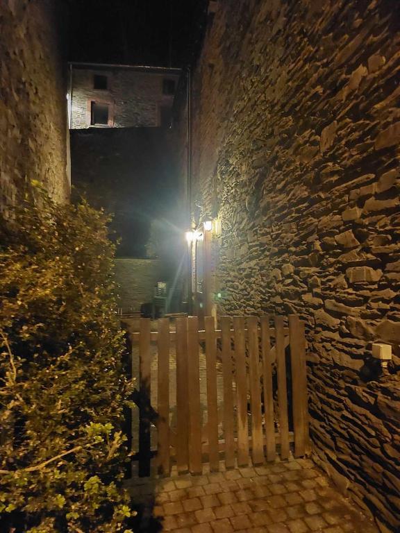 a wooden bench sitting next to a stone wall at night at Le Vieux La Roche in La-Roche-en-Ardenne