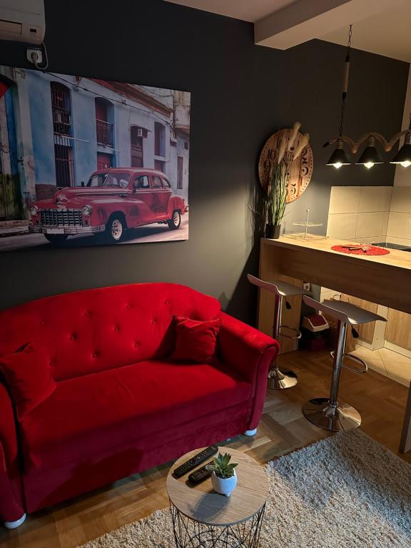 a living room with a red couch and a piano at Casa de Cuba in Novi Grad