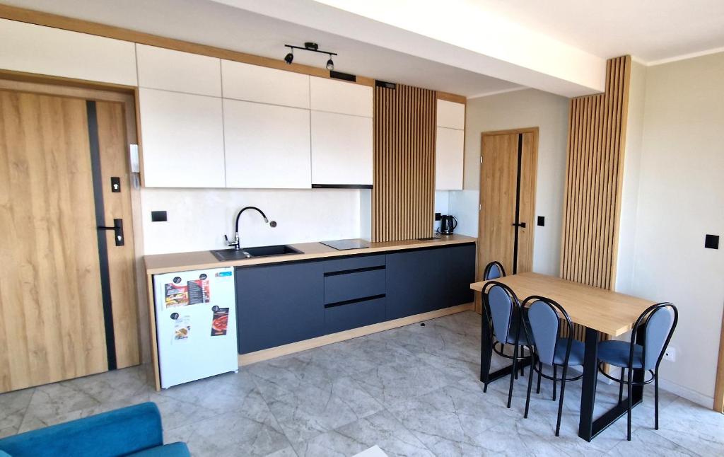 eine Küche mit einem Tisch und Stühlen sowie einem Kühlschrank in der Unterkunft Apartament Oliwia in Kluszkowce