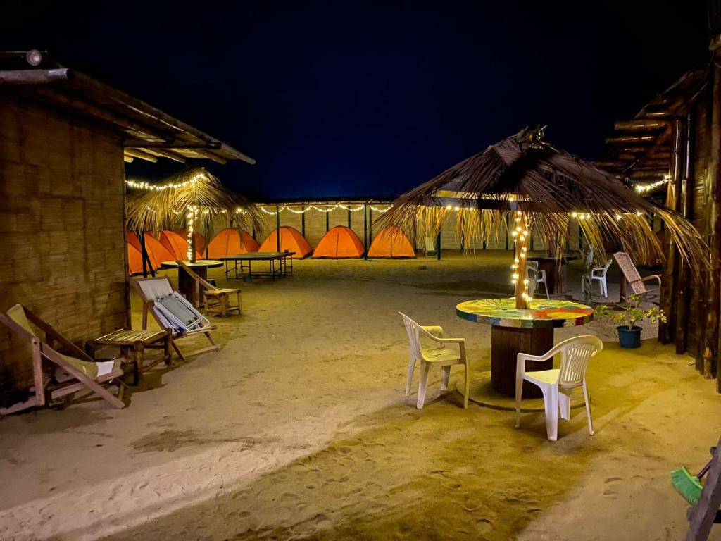 un grupo de mesas, sillas y tiendas de campaña por la noche en Pepon Surf Camp en Máncora
