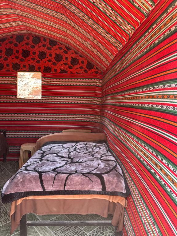 a bed in a room with a wall covered in stripes at Mars Stars Camp in Wadi Rum