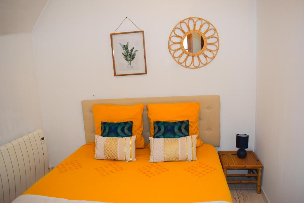 a bed with an orange blanket and pillows on it at Logement cozy proche du centre-ville in Poitiers