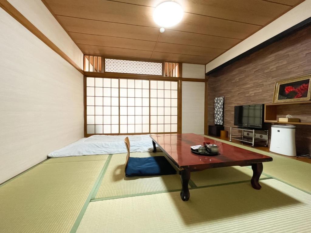 Eimiya Ryokan - Vacation STAY 36328v في أماكوسا: غرفة مع سرير وطاولة وسرير سيد