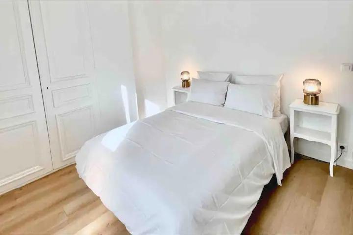 - une chambre blanche avec un lit blanc et deux lampes dans l'établissement Charming apartments 15 min away from Paris, à Argenteuil