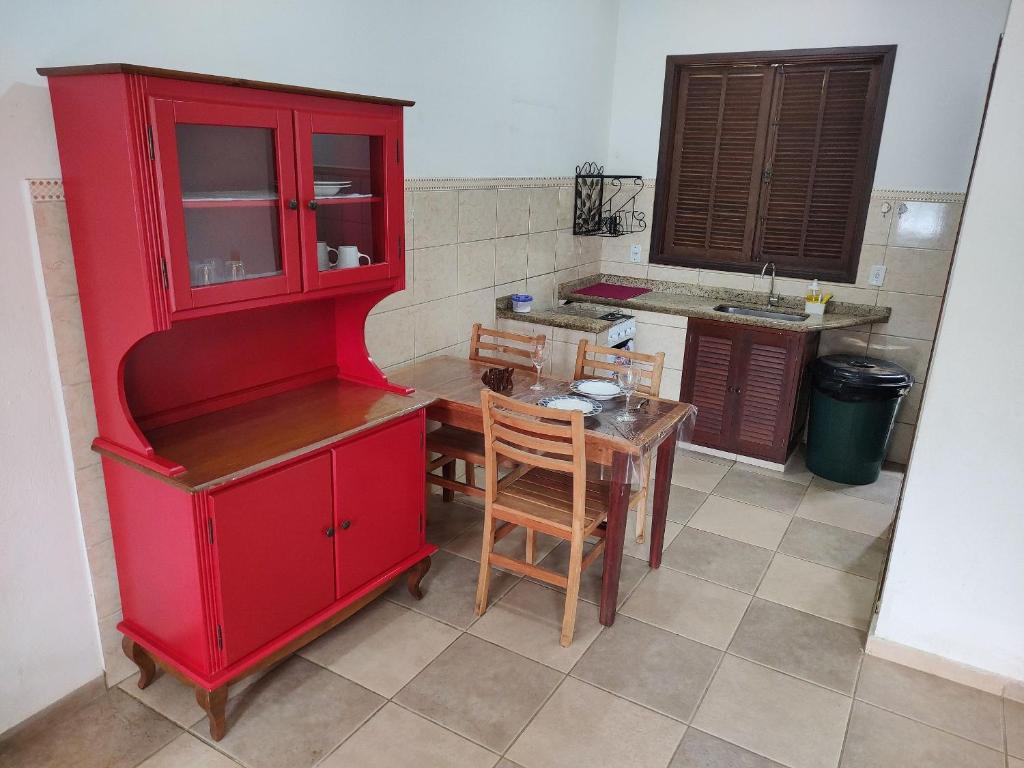 a kitchen with a red cabinet and a table at Casa 300 m Praia Jabaquara in Paraty