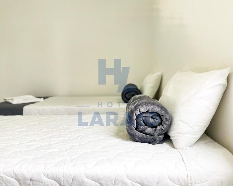 a white bed with a large gray pillow on it at Hotel Lara 10 Curitiba in Curitiba