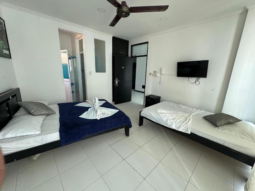1 dormitorio con 2 camas y TV de pantalla plana en AW Hotel Rodadero Suites, en Santa Marta