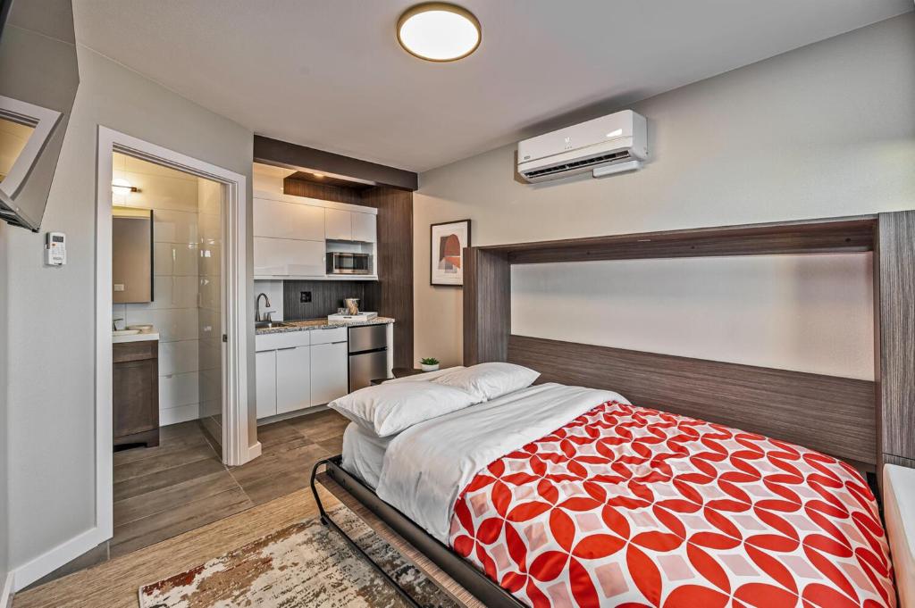 a bedroom with a red and white bed and a kitchen at Walkable Wonder Midtown Studio near Downtown Gems in Reno