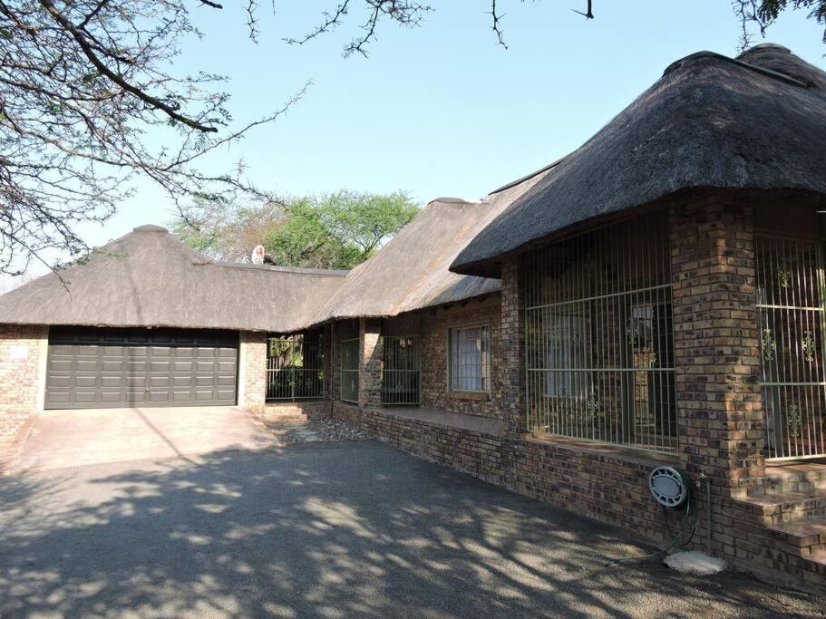 a large brick house with a thatched roof at Collin's Rest in Marloth Park