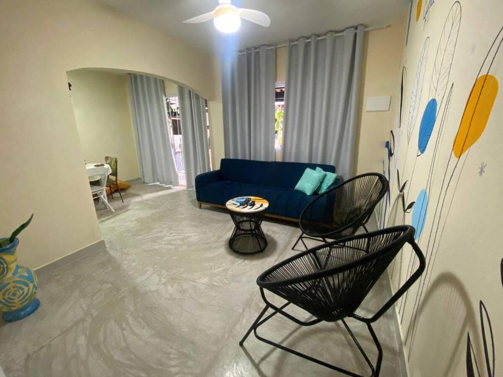 uma sala de estar com um sofá azul e cadeiras em Casinha da Nete (6 pessoas) em São Sebastião