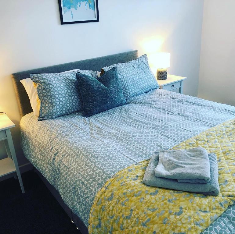 een bed met een blauw dekbed met een handdoek erop bij Bay View Bungalow Benllech, 5 Min Walk from Beach in Benllech