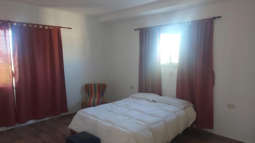 パラナにあるLa Casa de Soledadのベッドルーム1室(赤いカーテンと窓付きのベッド1台付)