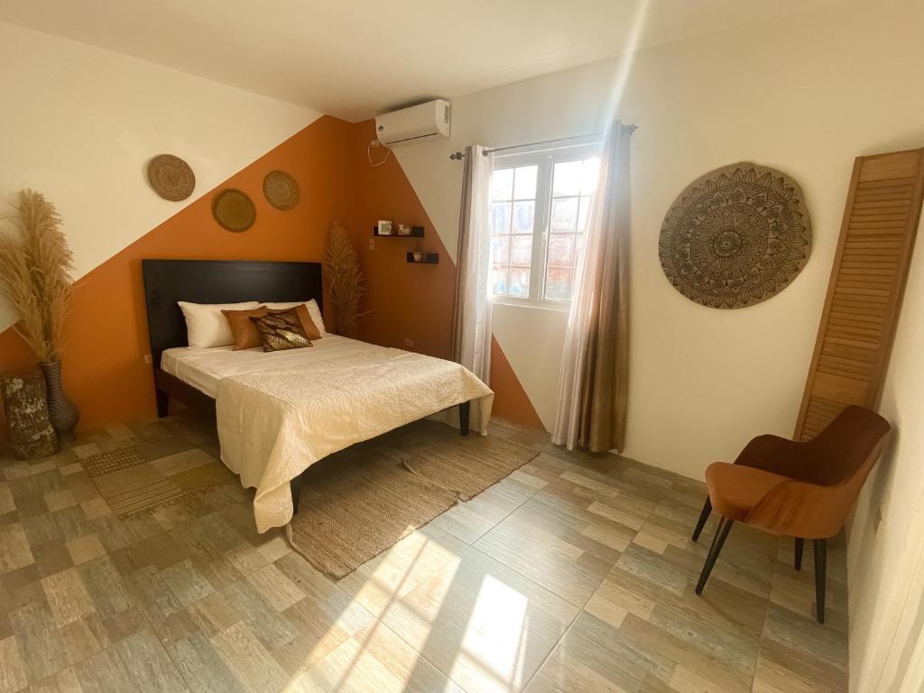 een slaapkamer met oranje muren en een bed en een stoel bij House of Zen in Santa Cruz