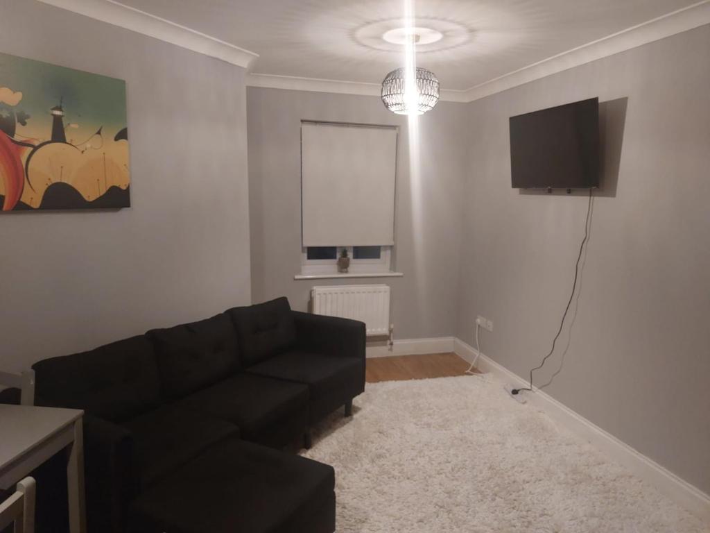 uma sala de estar com um sofá preto e uma televisão de ecrã plano em Short Stay at Dartford!!! em Dartford