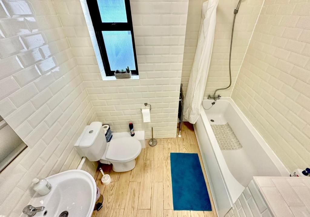 a bathroom with a toilet and a sink and a tub at Stay in Whitechapel apartment in London