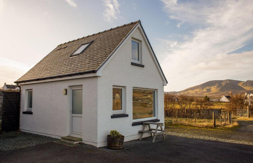 Uma casa branca com uma mesa de piquenique à frente. em Solas Alainn Chalet em Portree