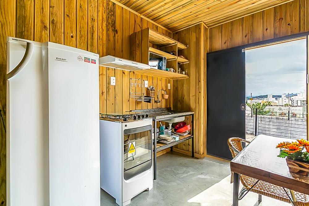 a kitchen with a white refrigerator and a table with a tableablish at Casa Próximo ao Centro com Vista para o Mar. in Florianópolis