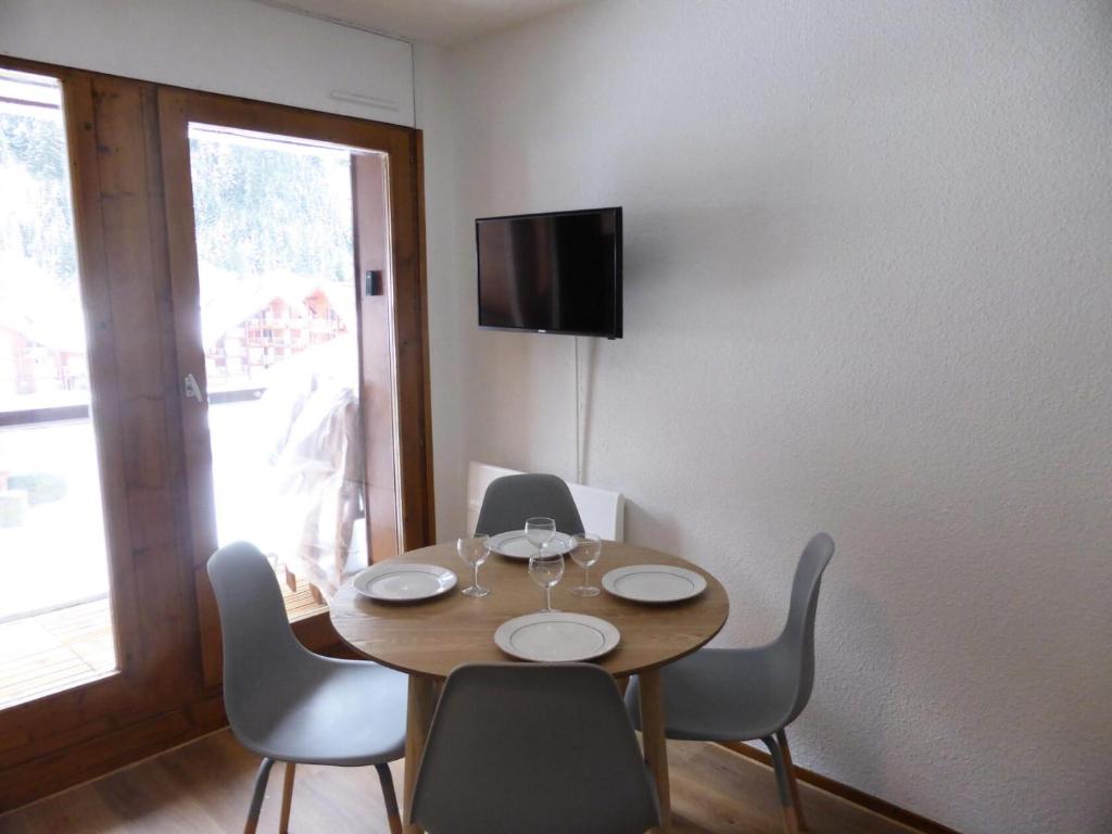 a dining room table with chairs and a television on a wall at Résidence Combettes - Studio pour 4 Personnes 071 in Les Contamines-Montjoie