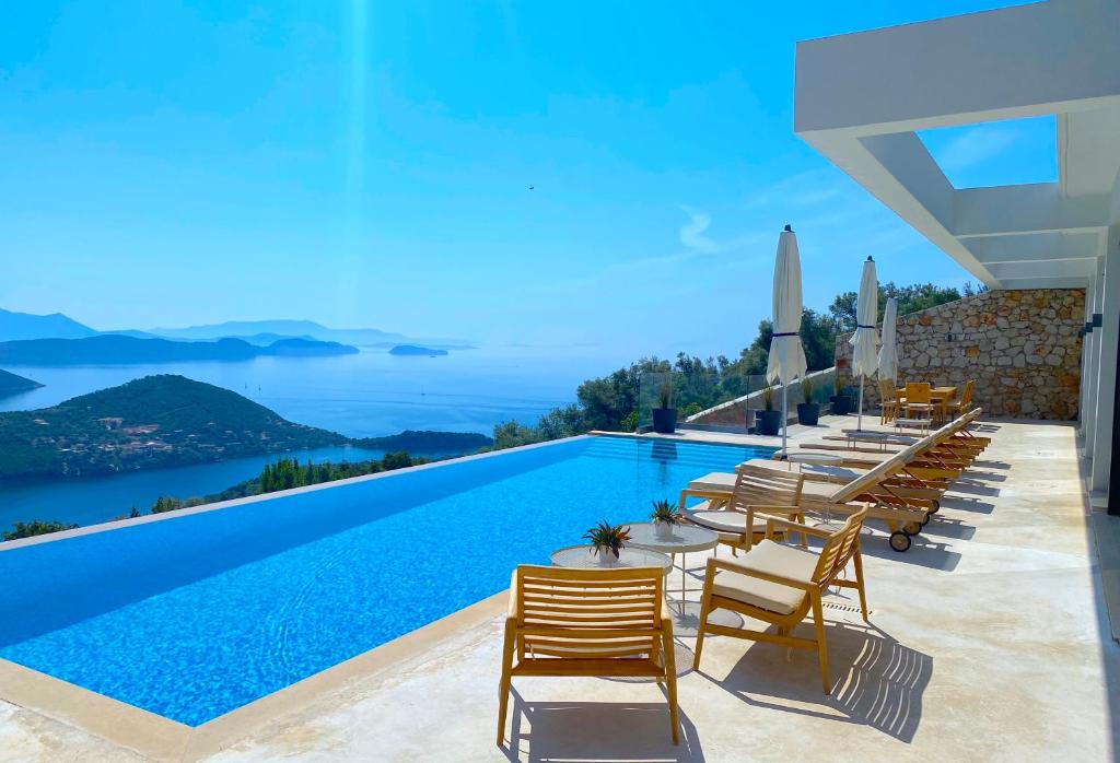 uma piscina com cadeiras e vista para o oceano em Villa ECO LUXE em Sivota