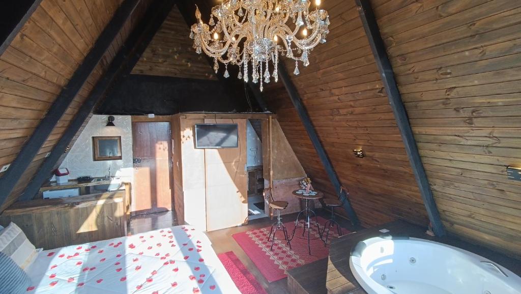 a room with a chandelier and a tub in a attic at Chalés Capivari Diamante in Campos do Jordão