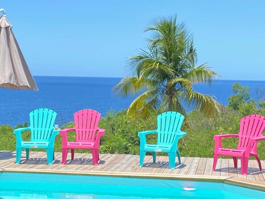 un grupo de cuatro sillas junto a una piscina en Domaine de la villa d’orge, en Vieux-Habitants