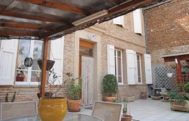 Lisle-sur-TarnにあるChambre d'Hôtes Chez Eliane et Bernardの屋外パティオ(ガラステーブル、鉢植えの植物付)