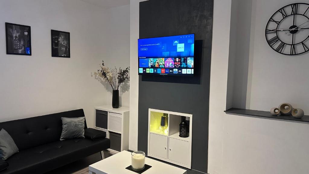 バーンリーにあるModern 2 Bed near Turf Moor Football Stadium, Parks, Canal and Lakeのリビングルーム(黒いソファ、時計付)