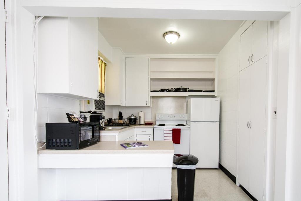 eine weiße Küche mit weißen Schränken und einem schwarzen Gerät in der Unterkunft Stay Condominiums Waikiki in Honolulu