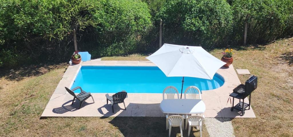 una piscina con sombrilla y sillas y una mesa con sombrilla en La più bella en Villa Carlos Paz