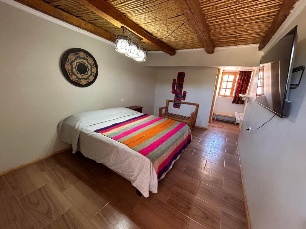 a bedroom with a bed with a colorful blanket at Puna Hostel in San Pedro de Atacama