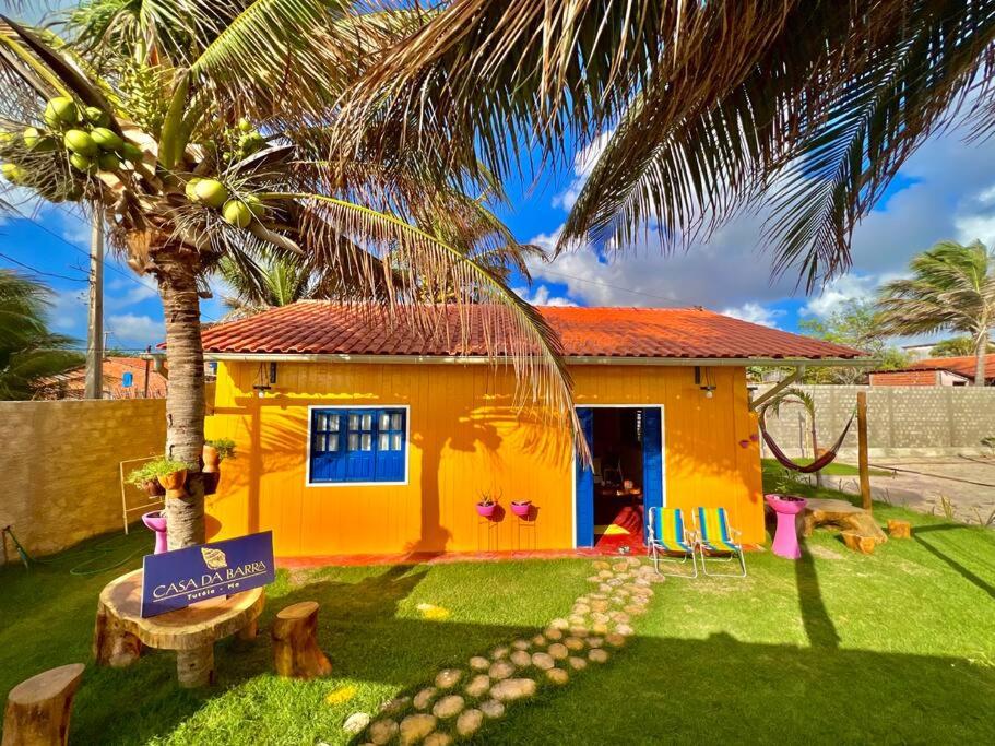 a small yellow house with a palm tree in front of it at Casa de Praia Tutóia in Tutóia